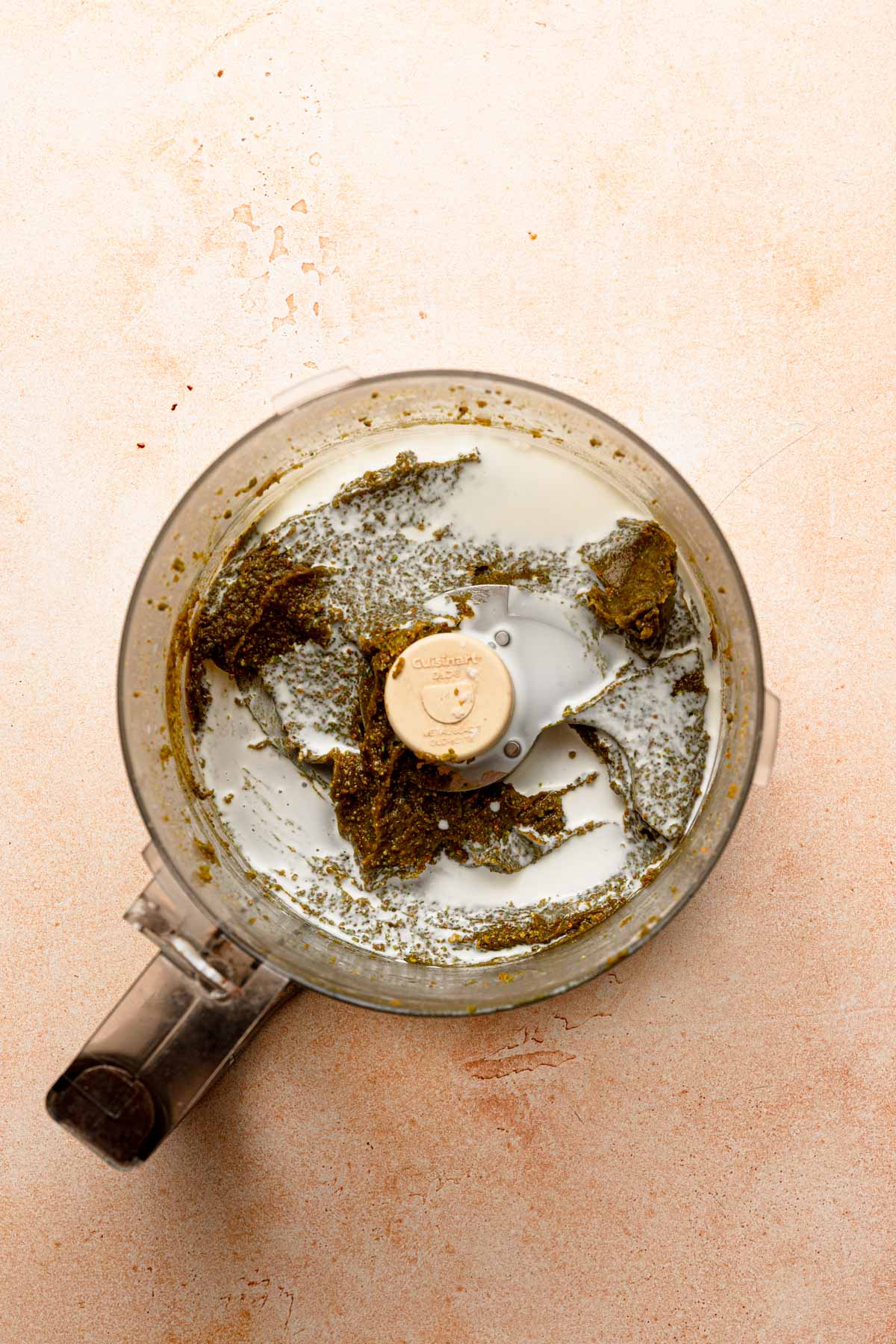 A food processor bowl with pistachios paste and cream.