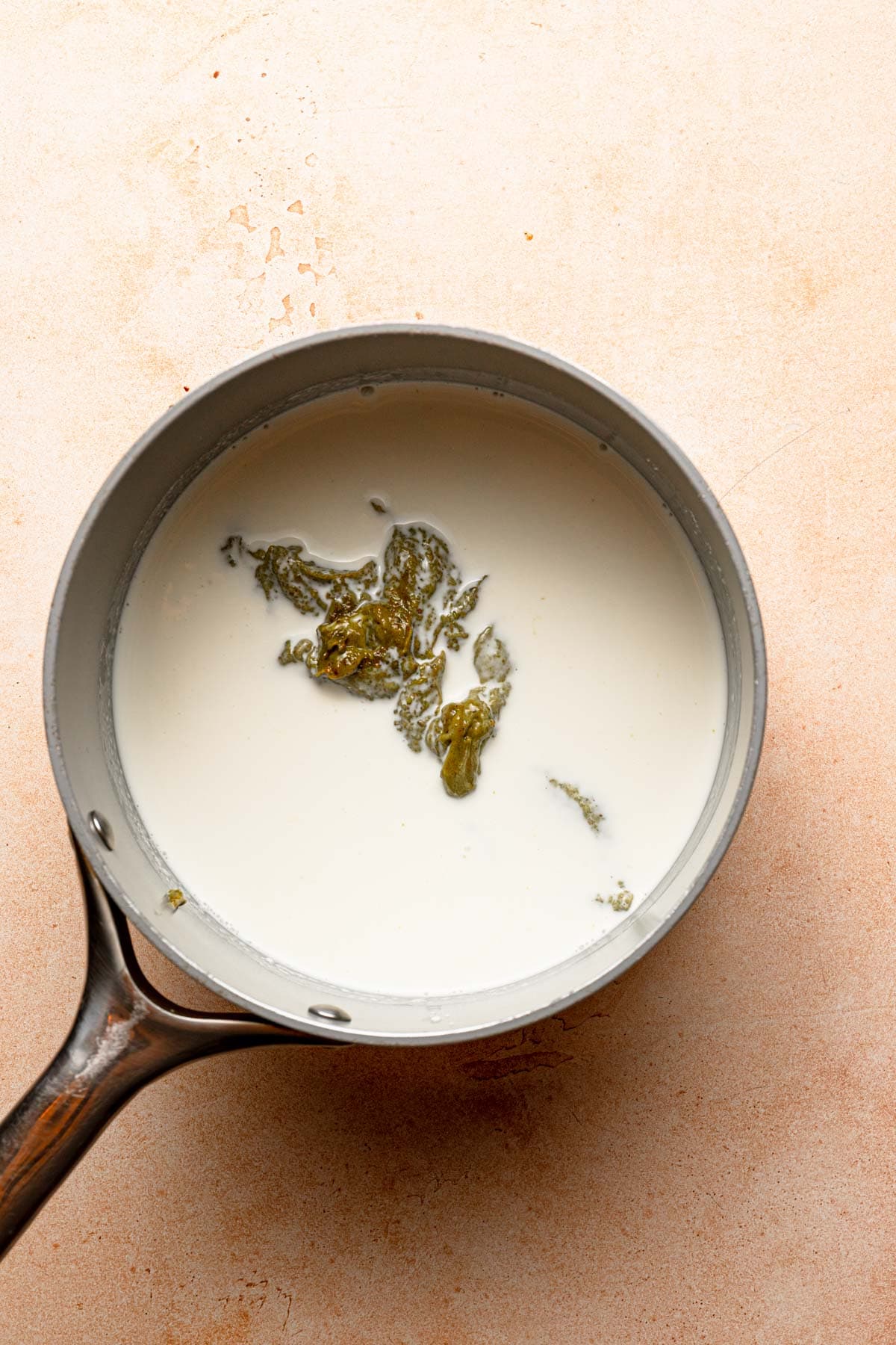 A sauce pan with milk and pistachio cream.