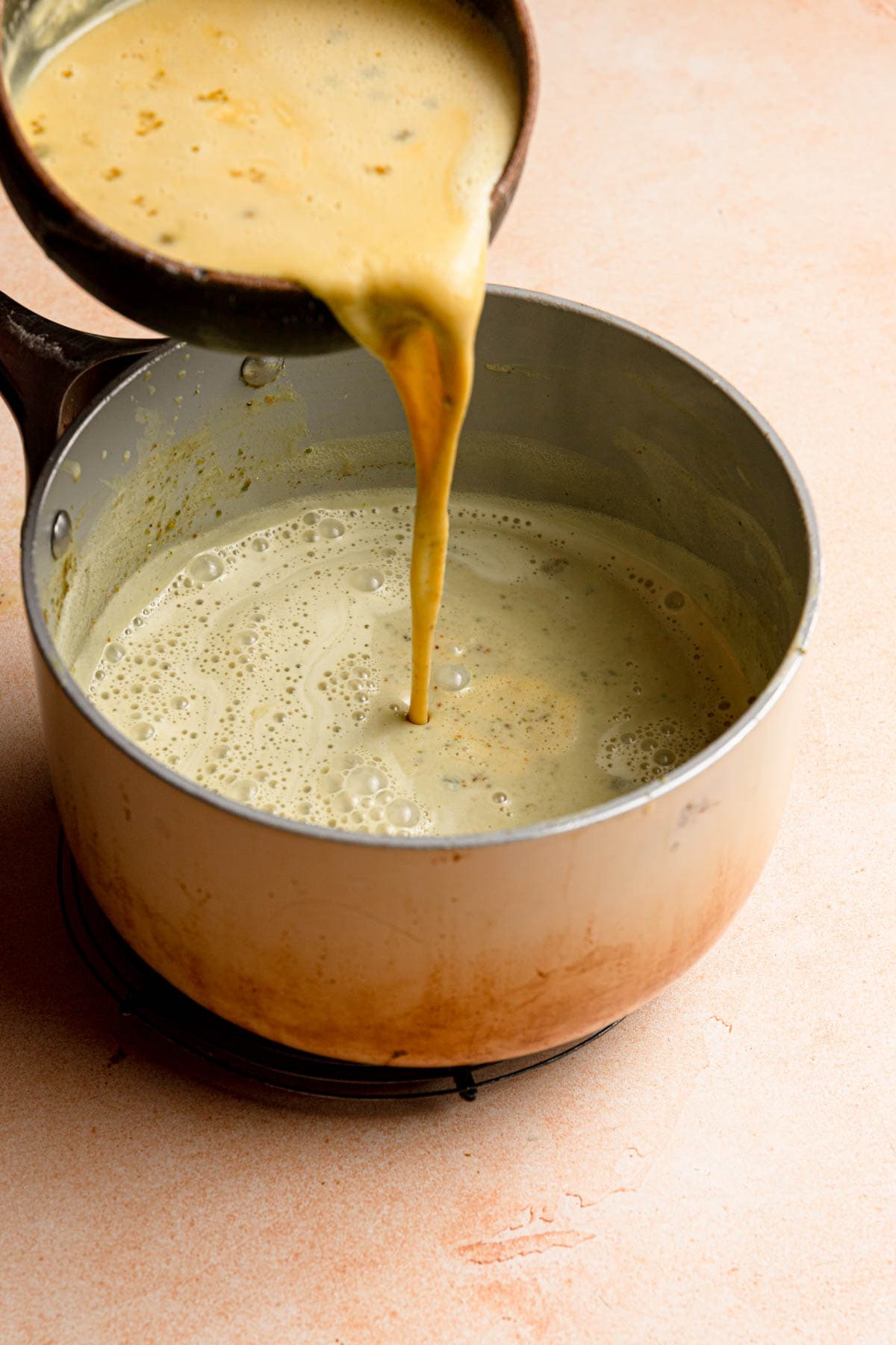 Pouring egg mixture into a saucepan with pisatchio milk.