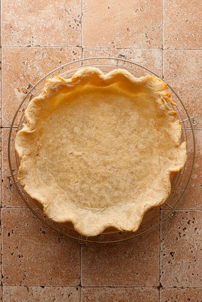A par-baked pie crust over a cooling wrack.