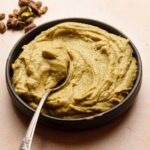 Pistachio pastry cream in a bowl with a spoon.