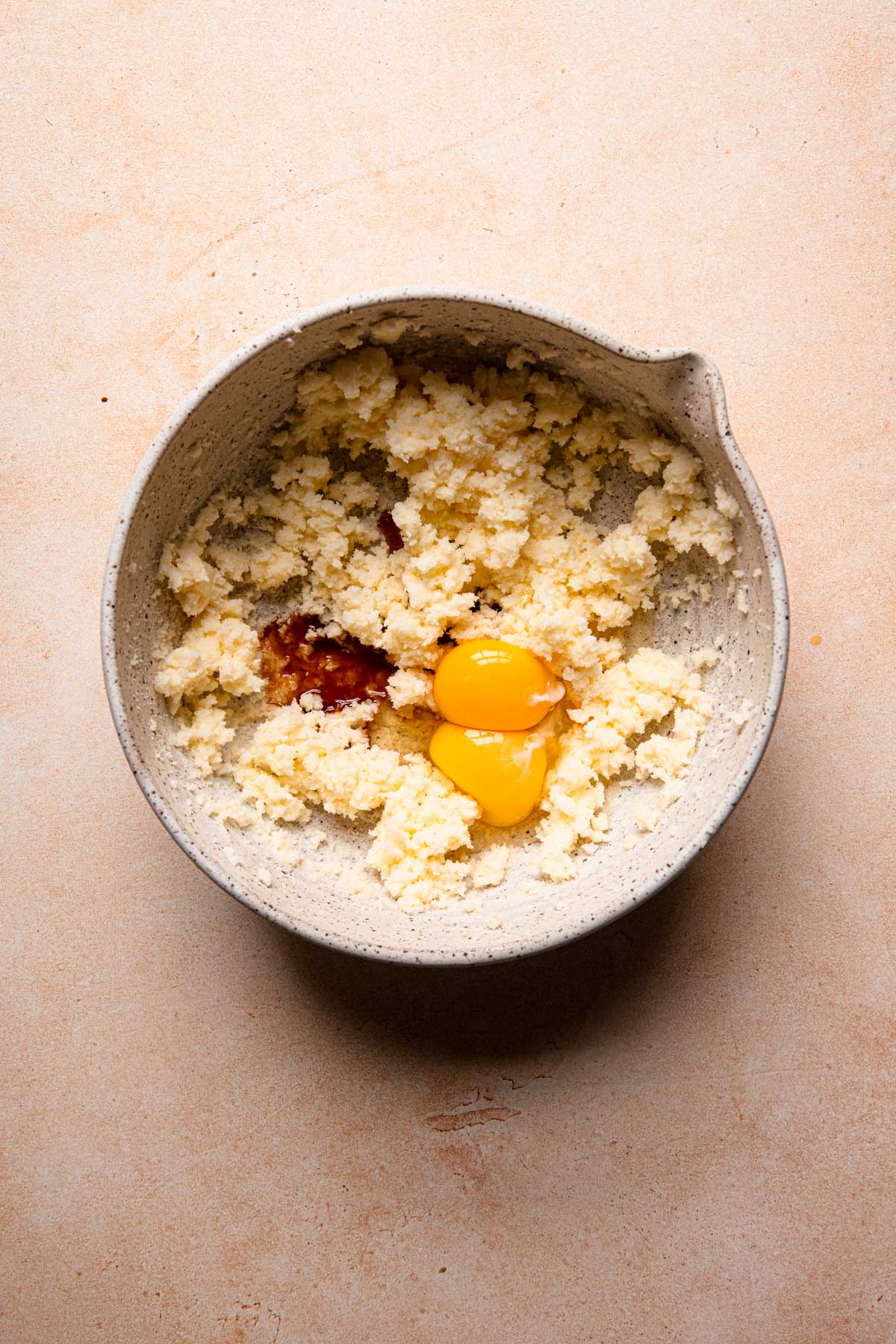 A large bowl with creamed butter, eggs and vanilla extract.