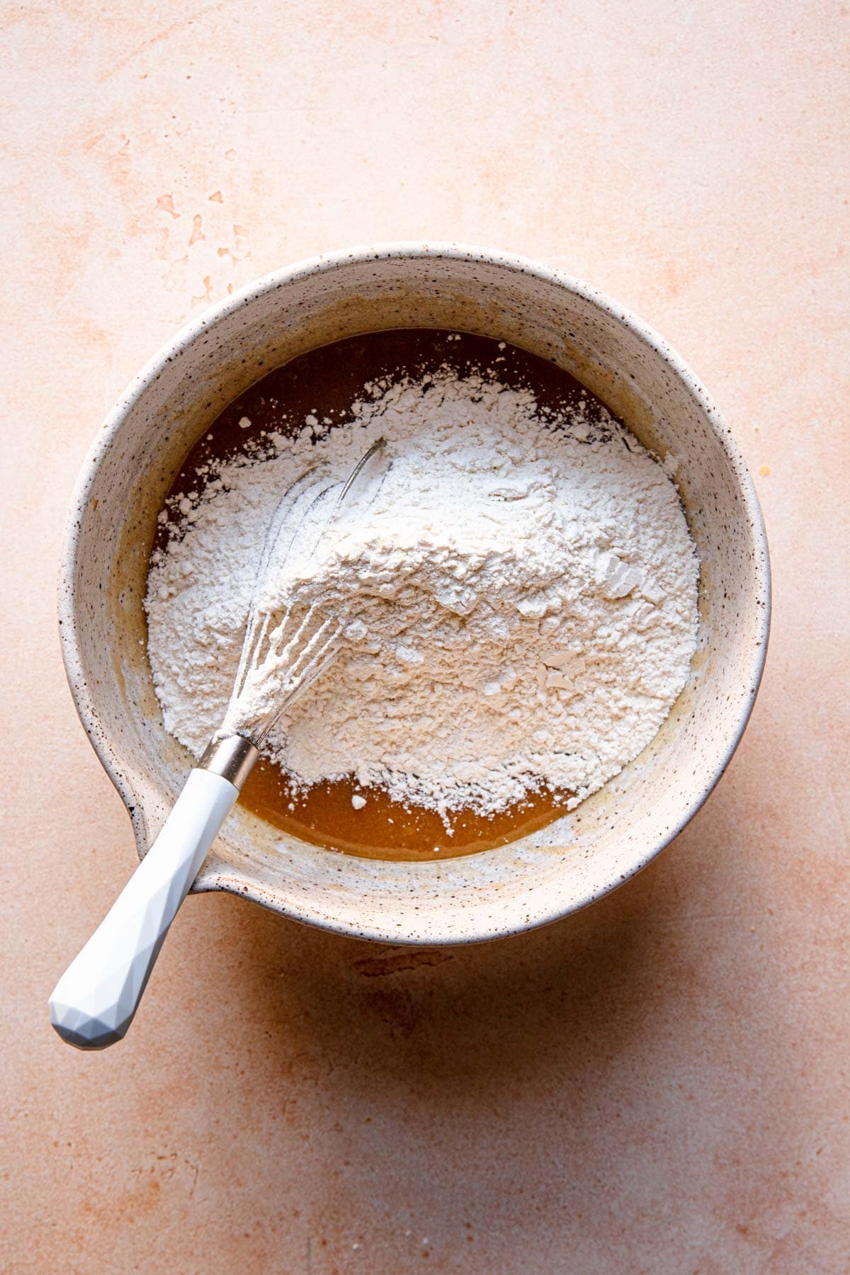 A large bowl with melted butter a flour and a whisk.
