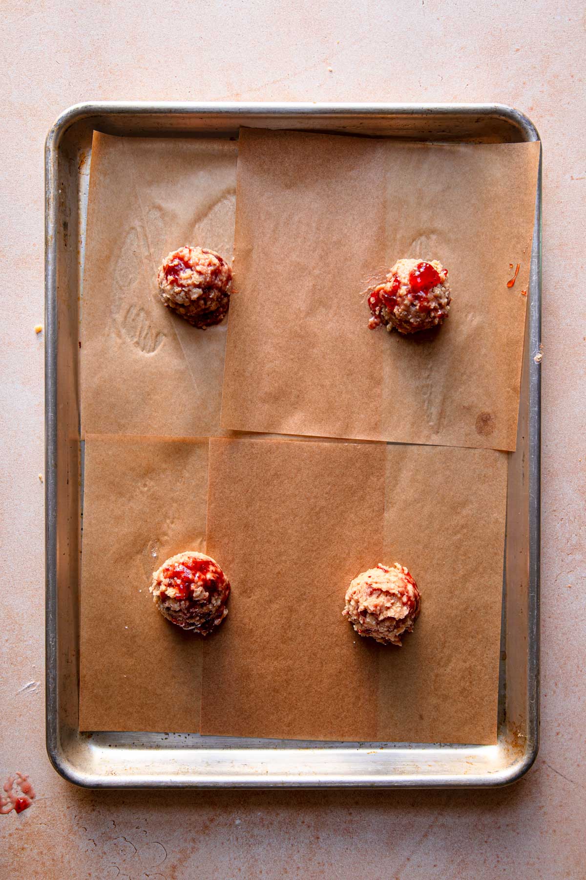 A pan with parchment paper and unbaked cookie balls.