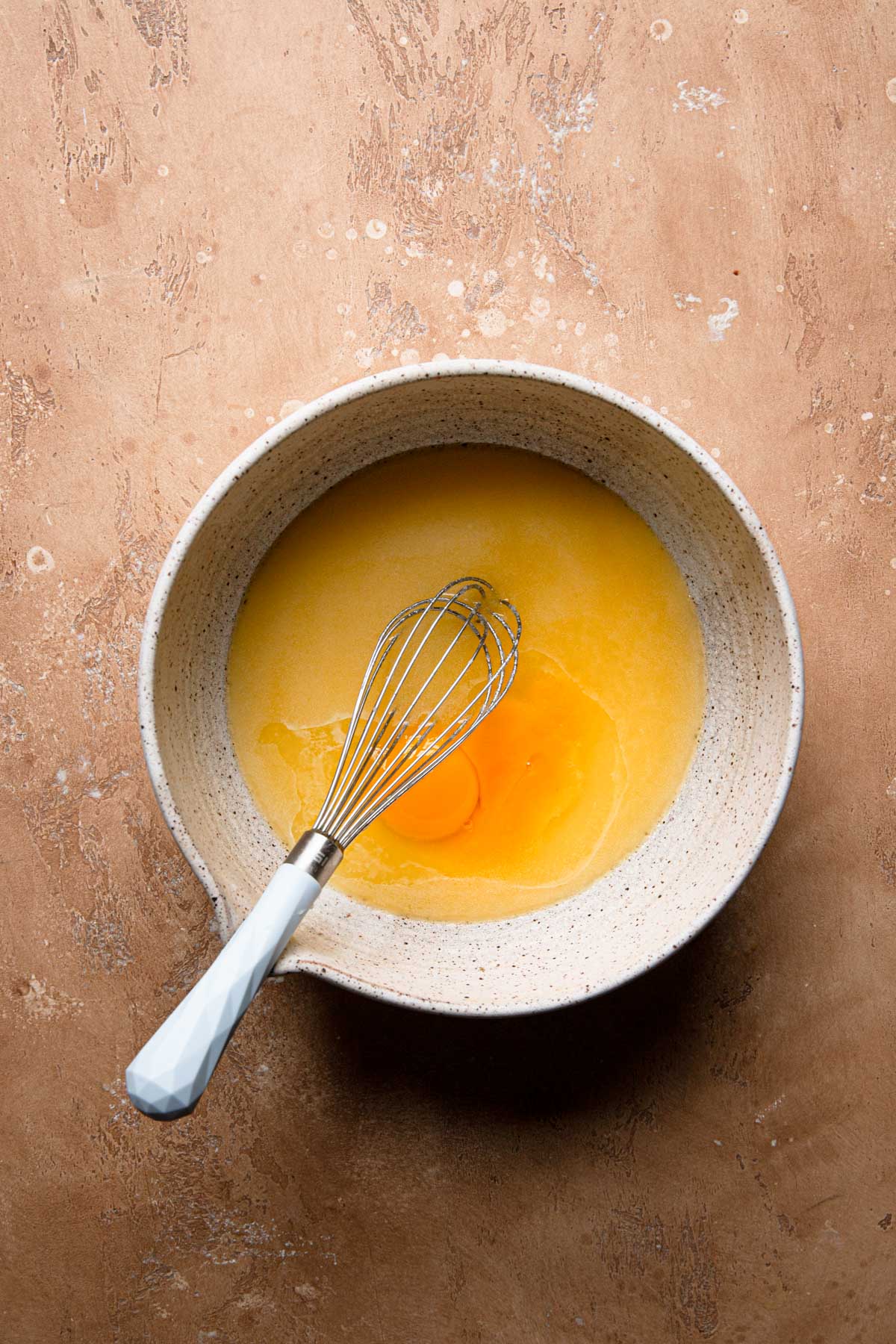 A large bowl with melted butter, eg yolks and a whisk.