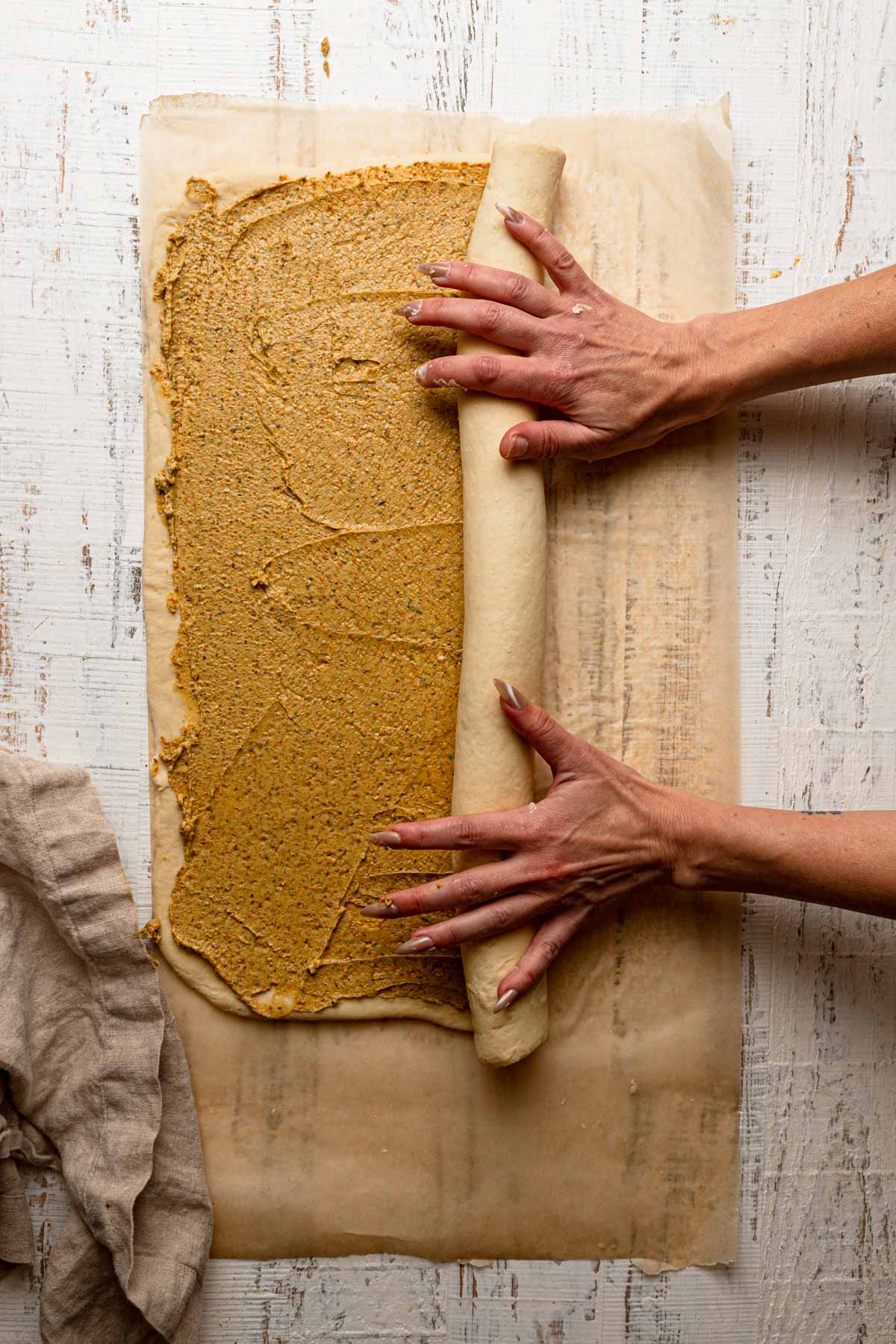 Hands rolling dough into a log.