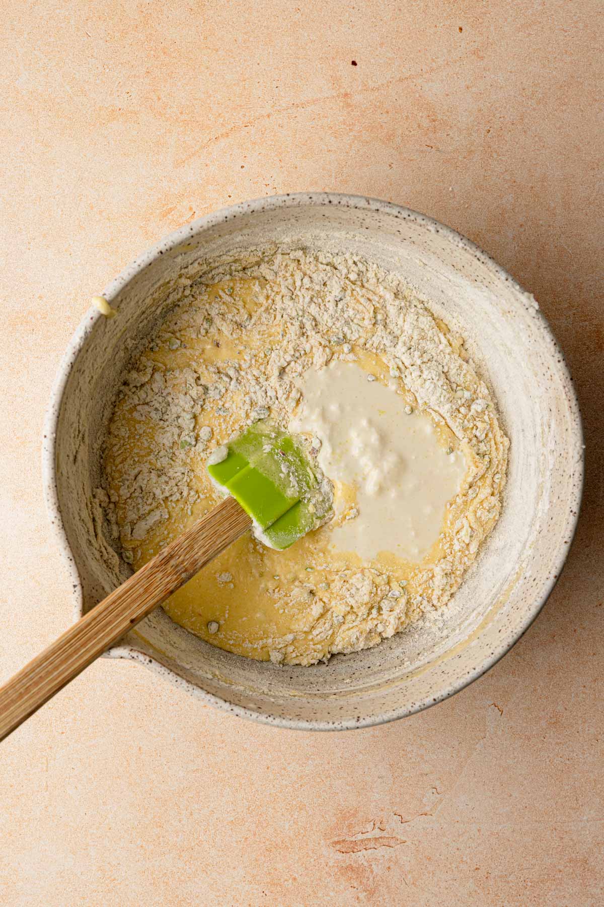 A large bowl raw batter and flour with a rubber spatula.