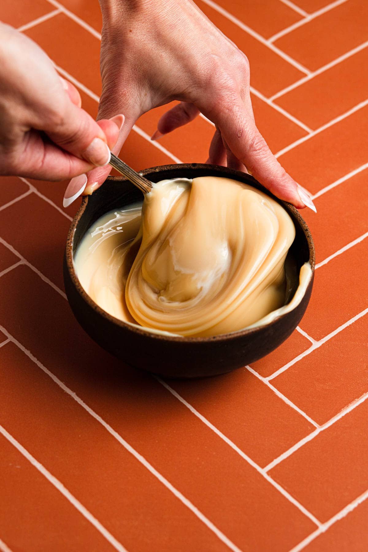 Stirring sweetened condensed milk in a bowl.