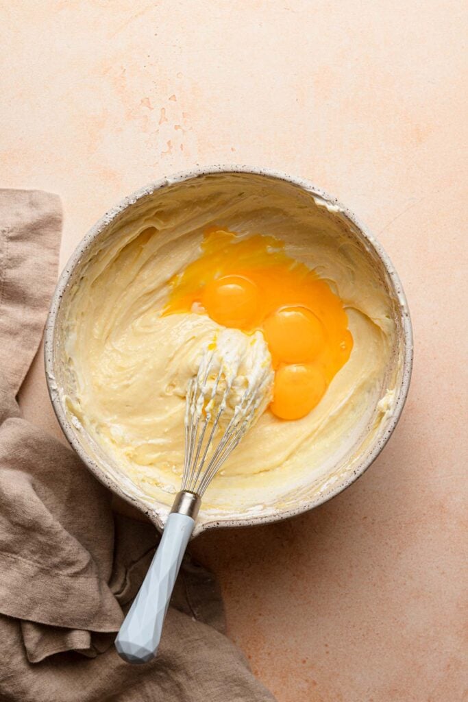 A large bowl with cream mixture, egg yolks, and a whisk.