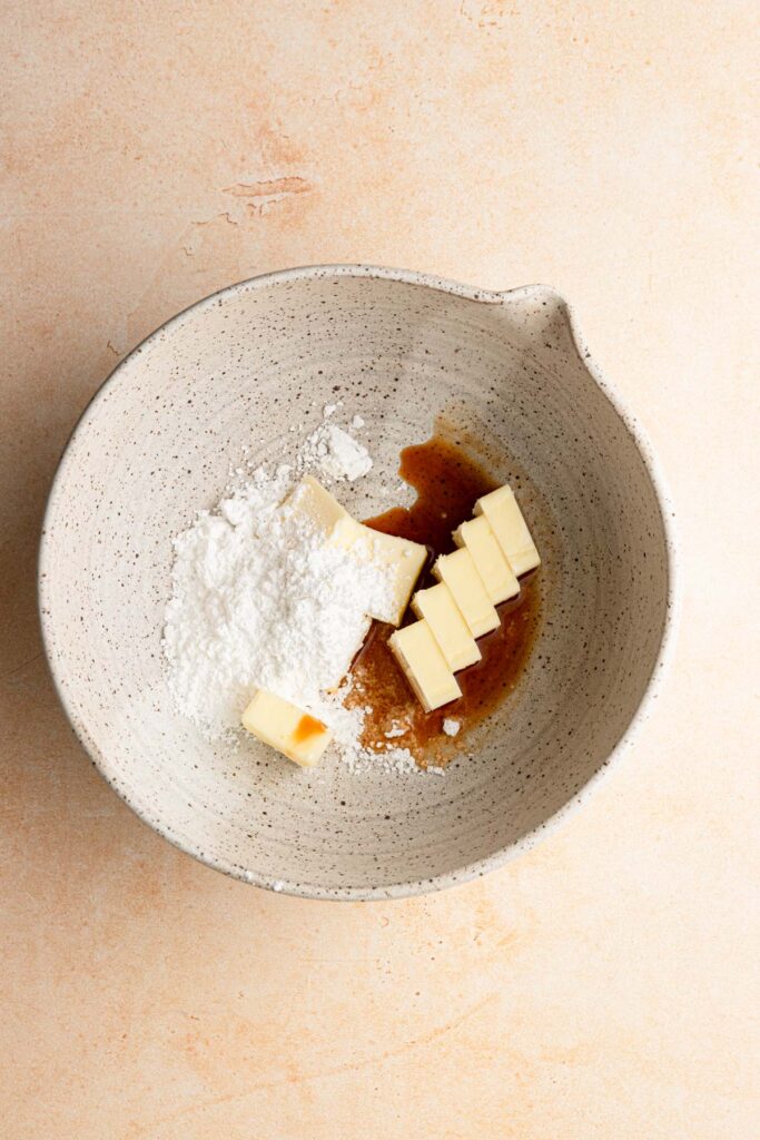 A large bowl with butter, powdered sugar and vanilla extract.