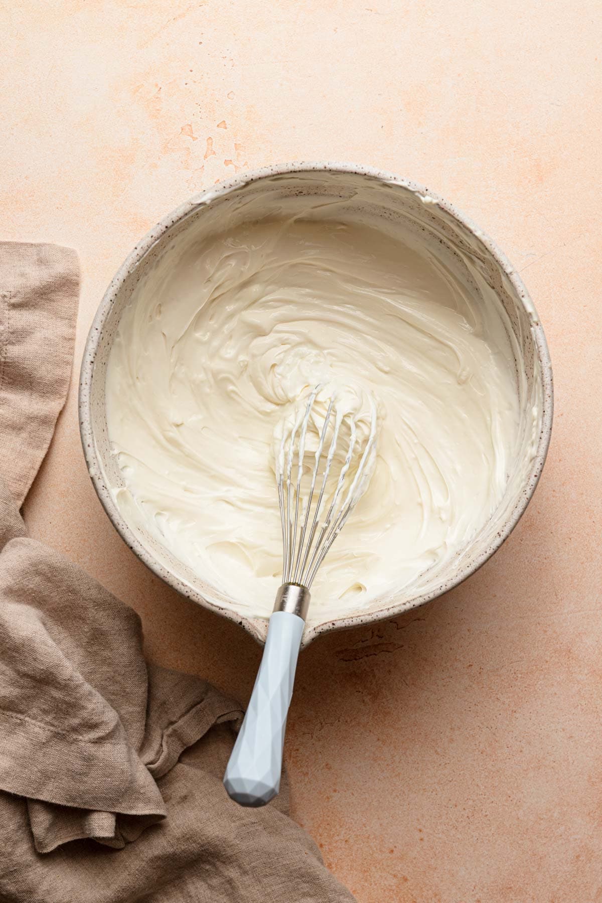 A large bowl with cream mixture and a whisk.