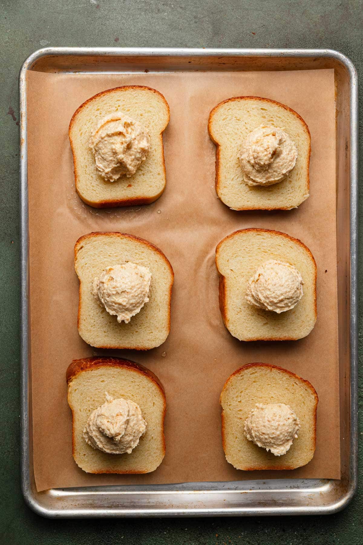 Brioche slices on a baking sheet with parchment paper and almond cream.