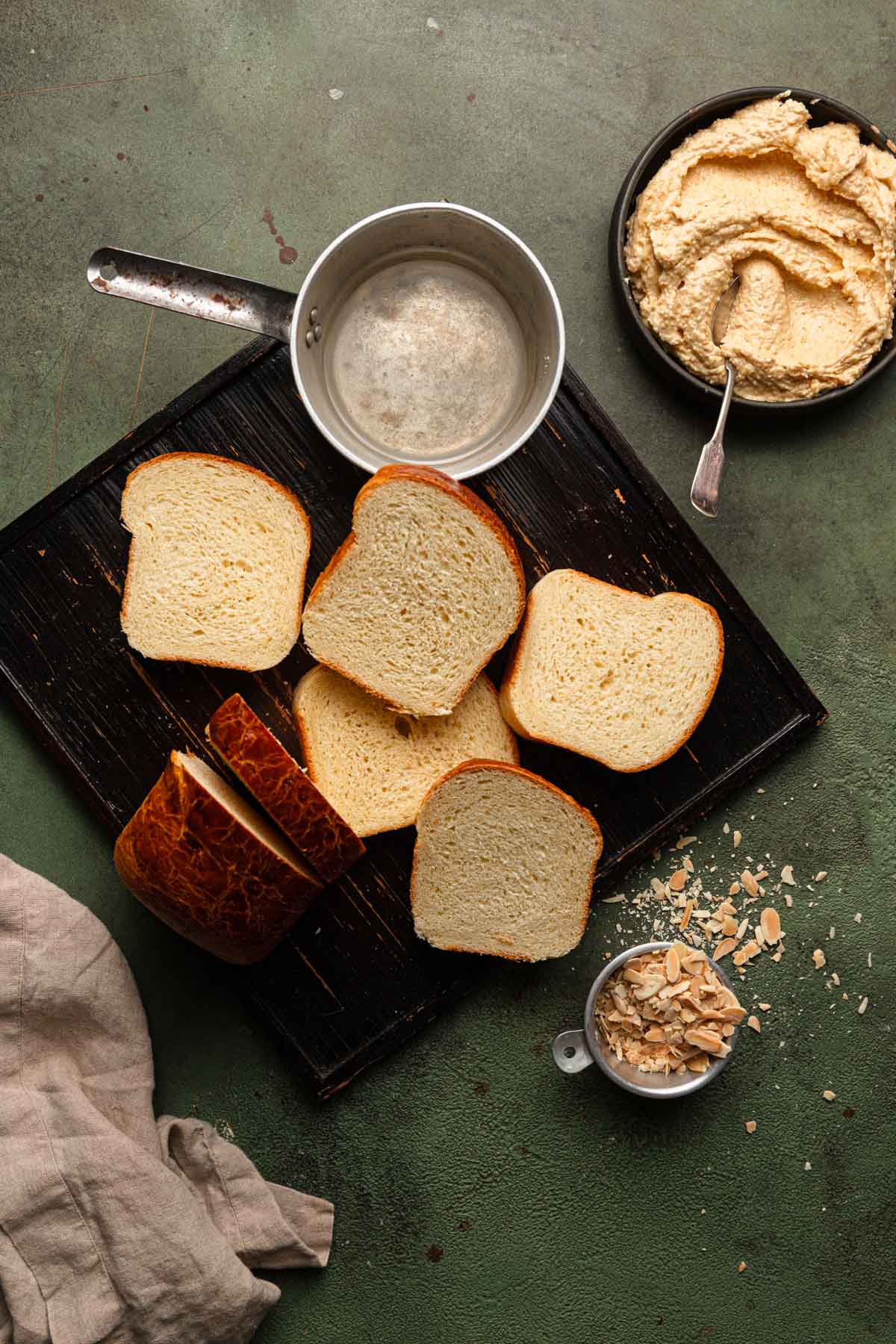 sliced brioche bread with syrup in a pan and almond cream in abowl.