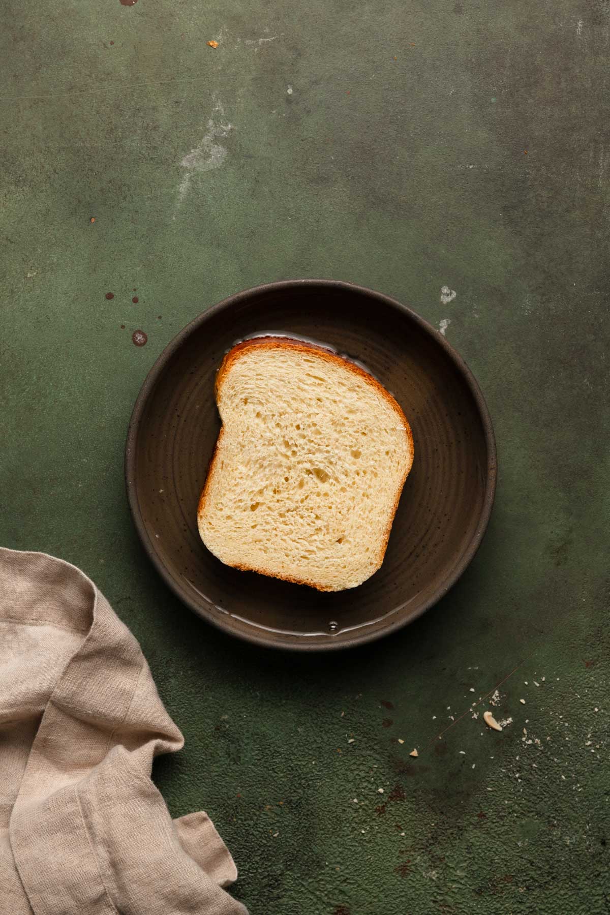 Brioche bread slice in a bowl with syrup.