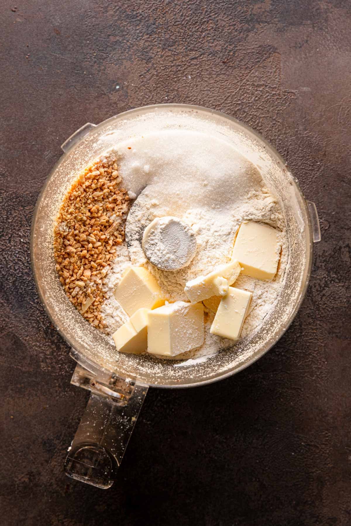 A food processor bowl with ground almonds, sugar, butter and flour.
