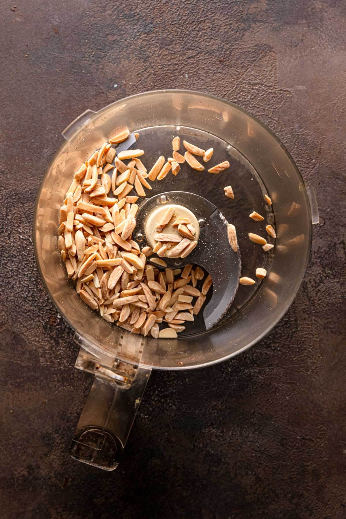 A food processor bowl with almonds.