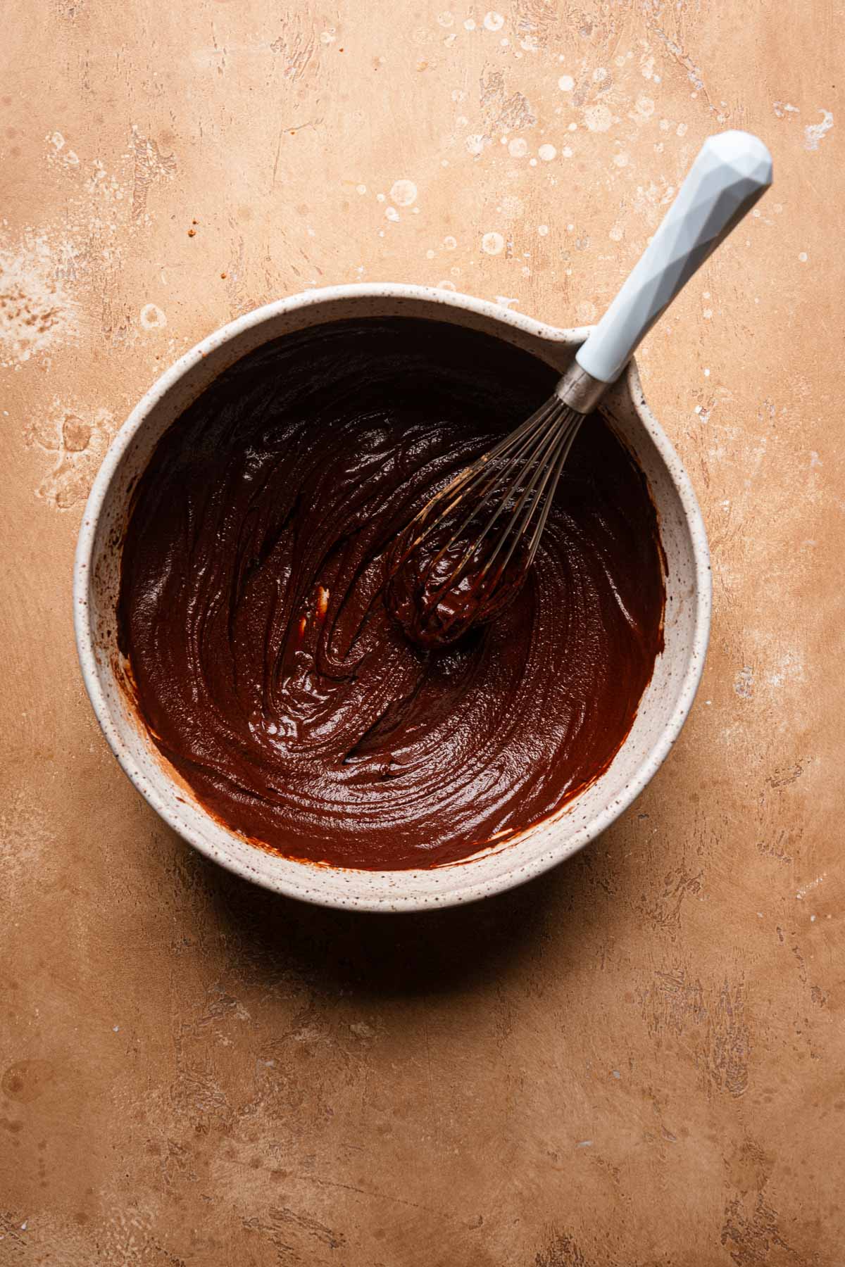 a bowl with melted chocolate and a whisk.