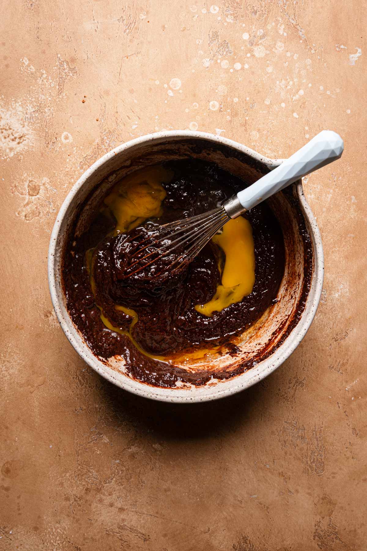 a bowl with melted chocolate and eggs with a whisk.