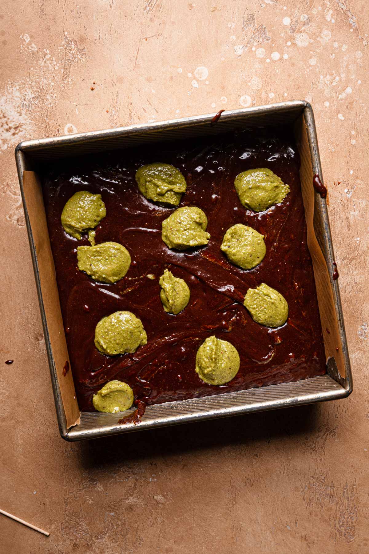 Brownie batter dotted with pistachio cream.
