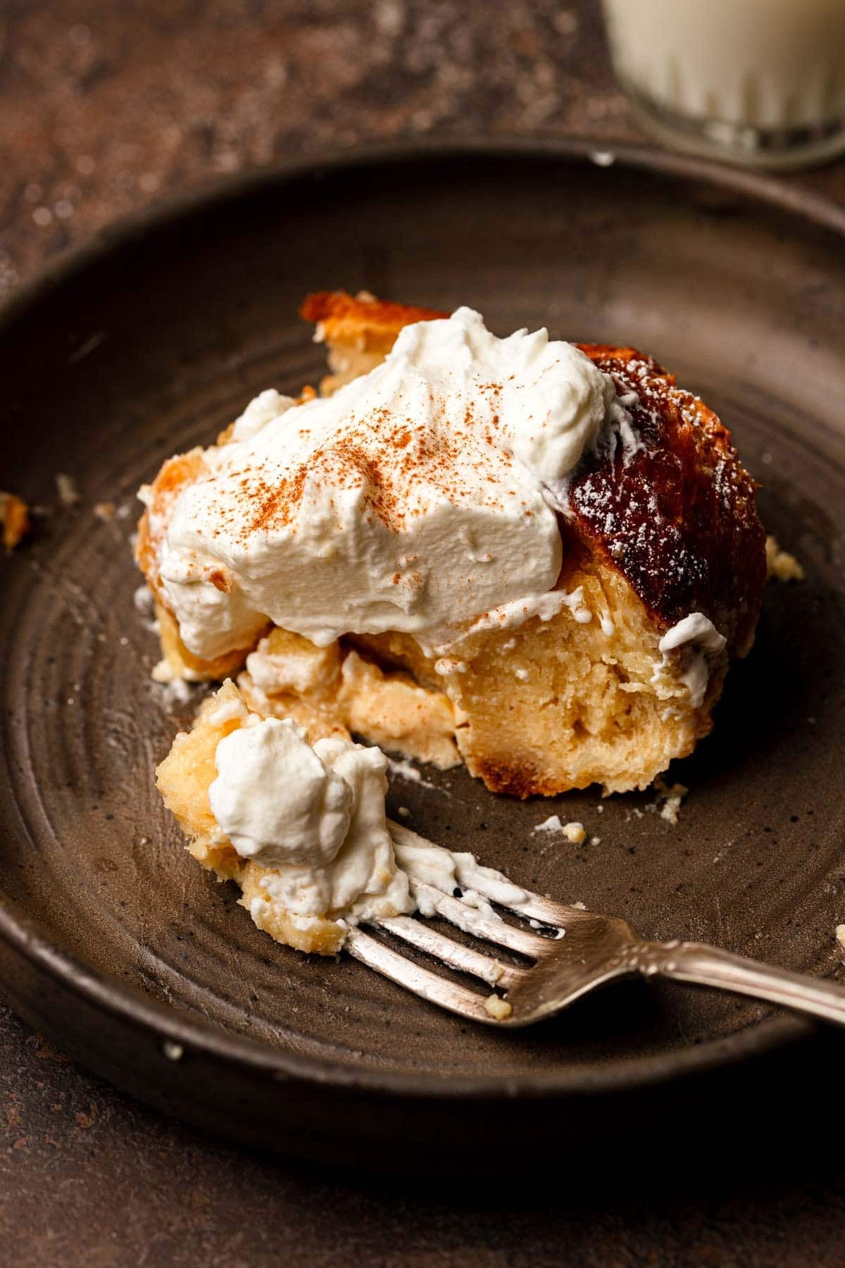 A slice of bread pudding topped with cream and a dust of cinnamon.
