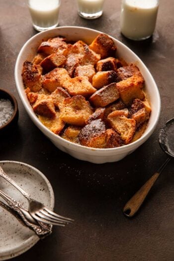 brioche bread pudding in a dish with milk, plates and forks.