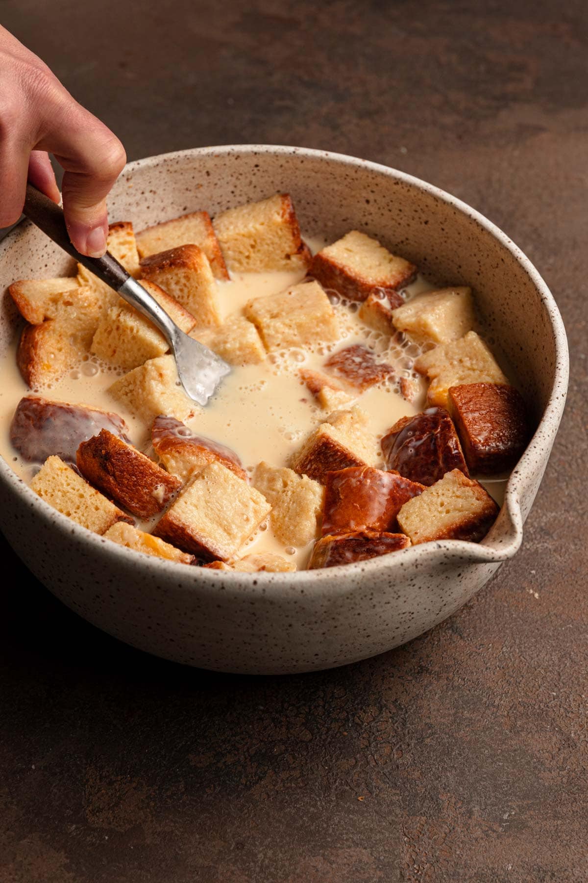 Pressing brioche bread into custard.
