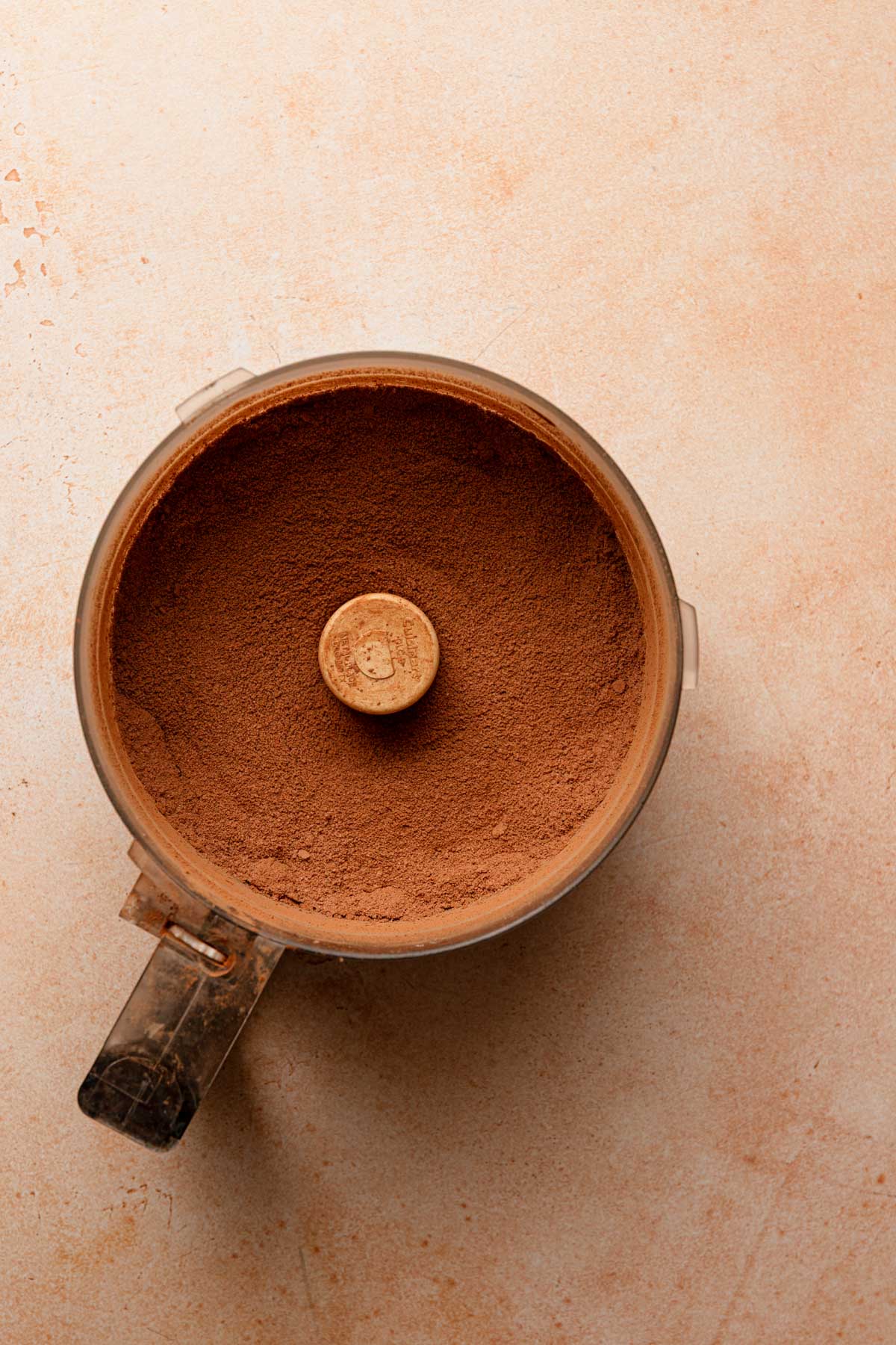 A food processor bowl with cocoa powder mixture.