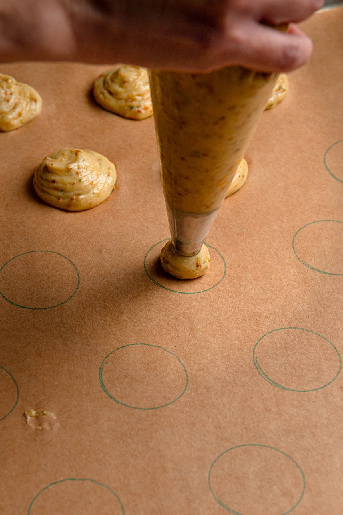 Piping cream puffs dough over a baking sheet.