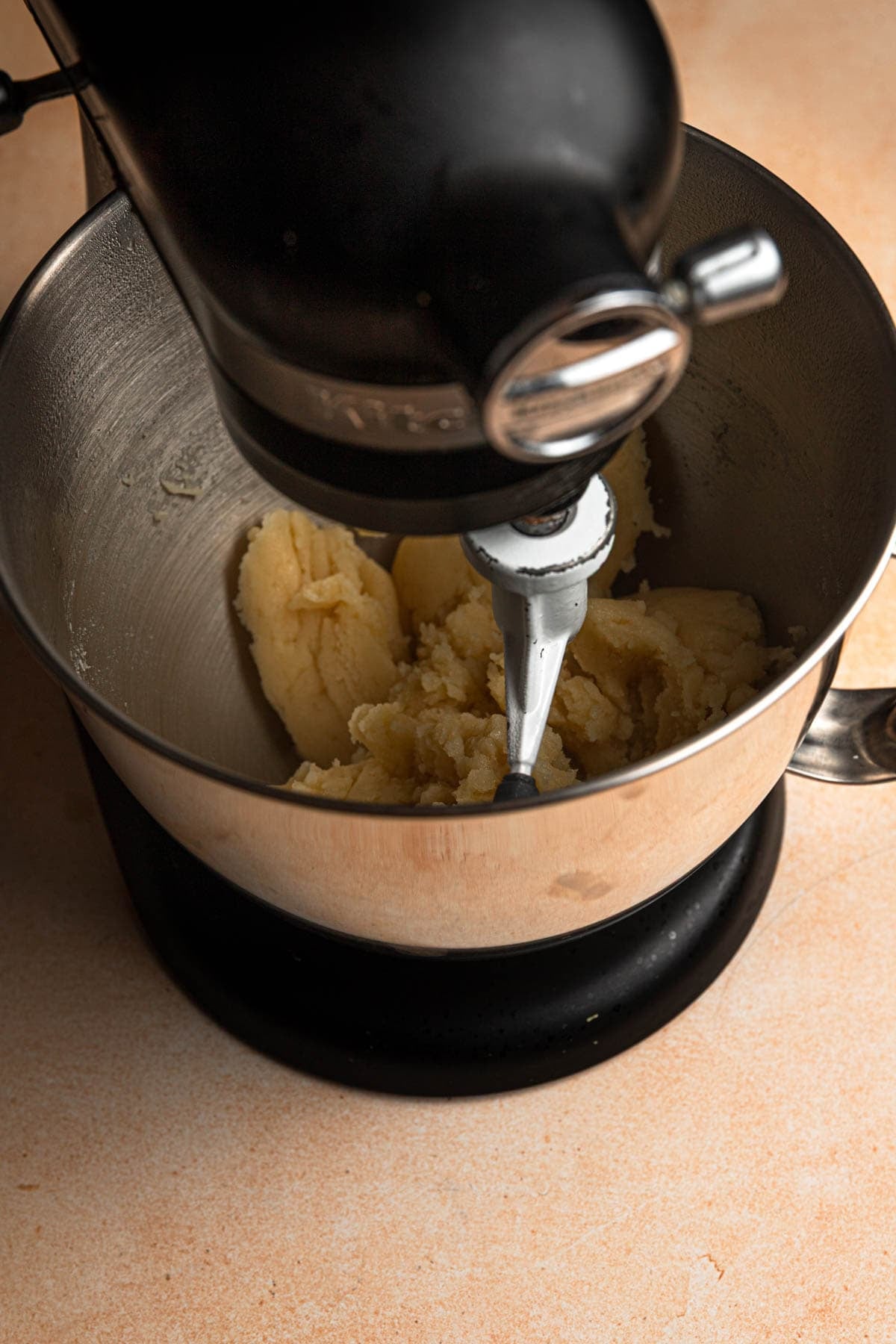 A stand mixer with a bowl and choux paste dough.