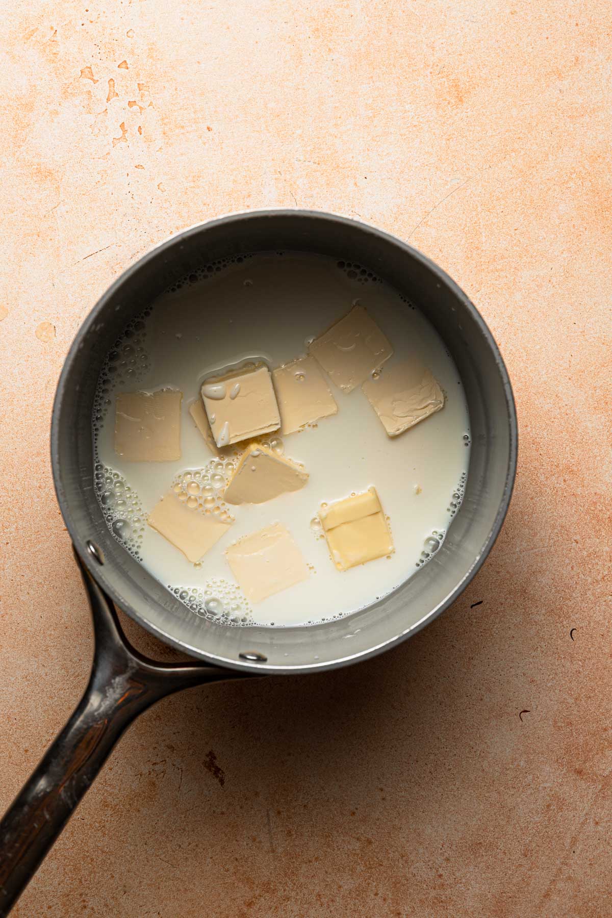 A sauce pan with milk and sliced butter.