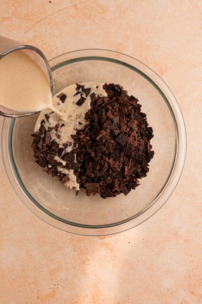 Pouring cream into a bowl with chopped chocolate. 