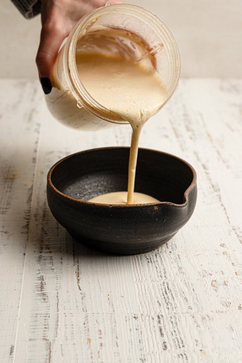 A hang pouring batter into a bowl.