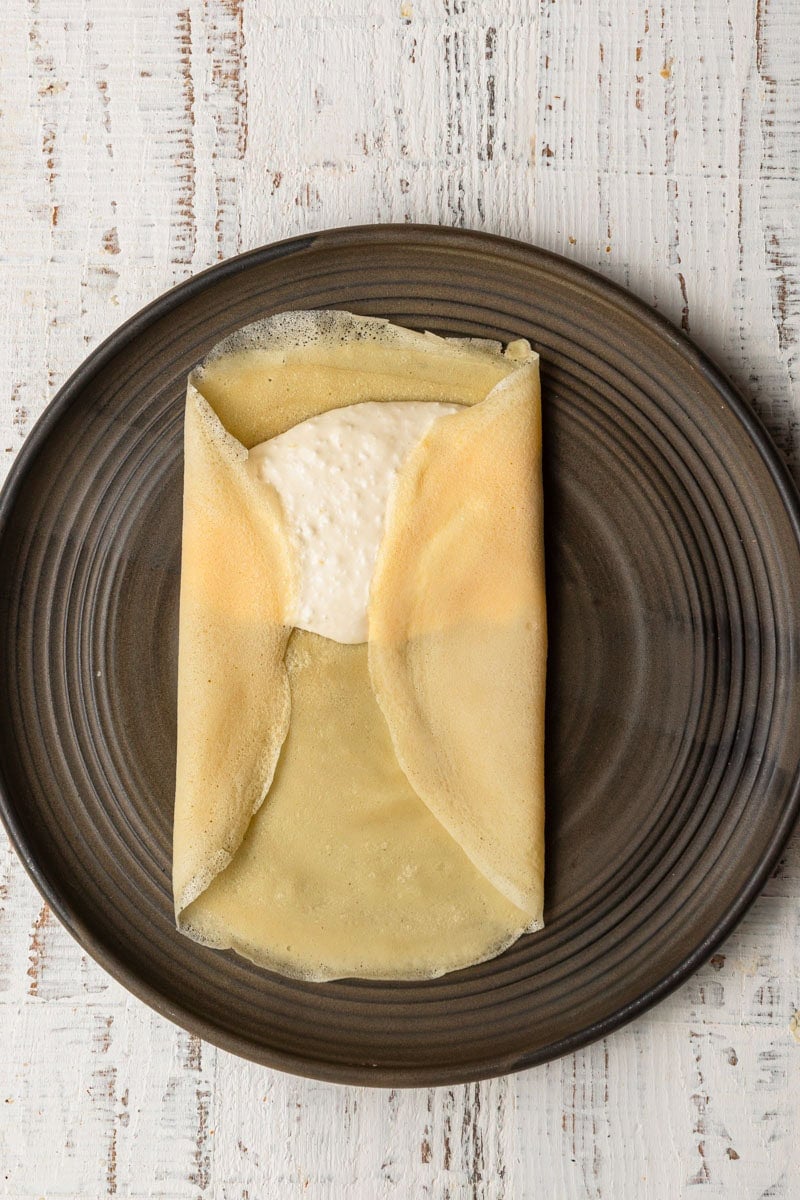 A plate topped with crepe topped with cheese filling.