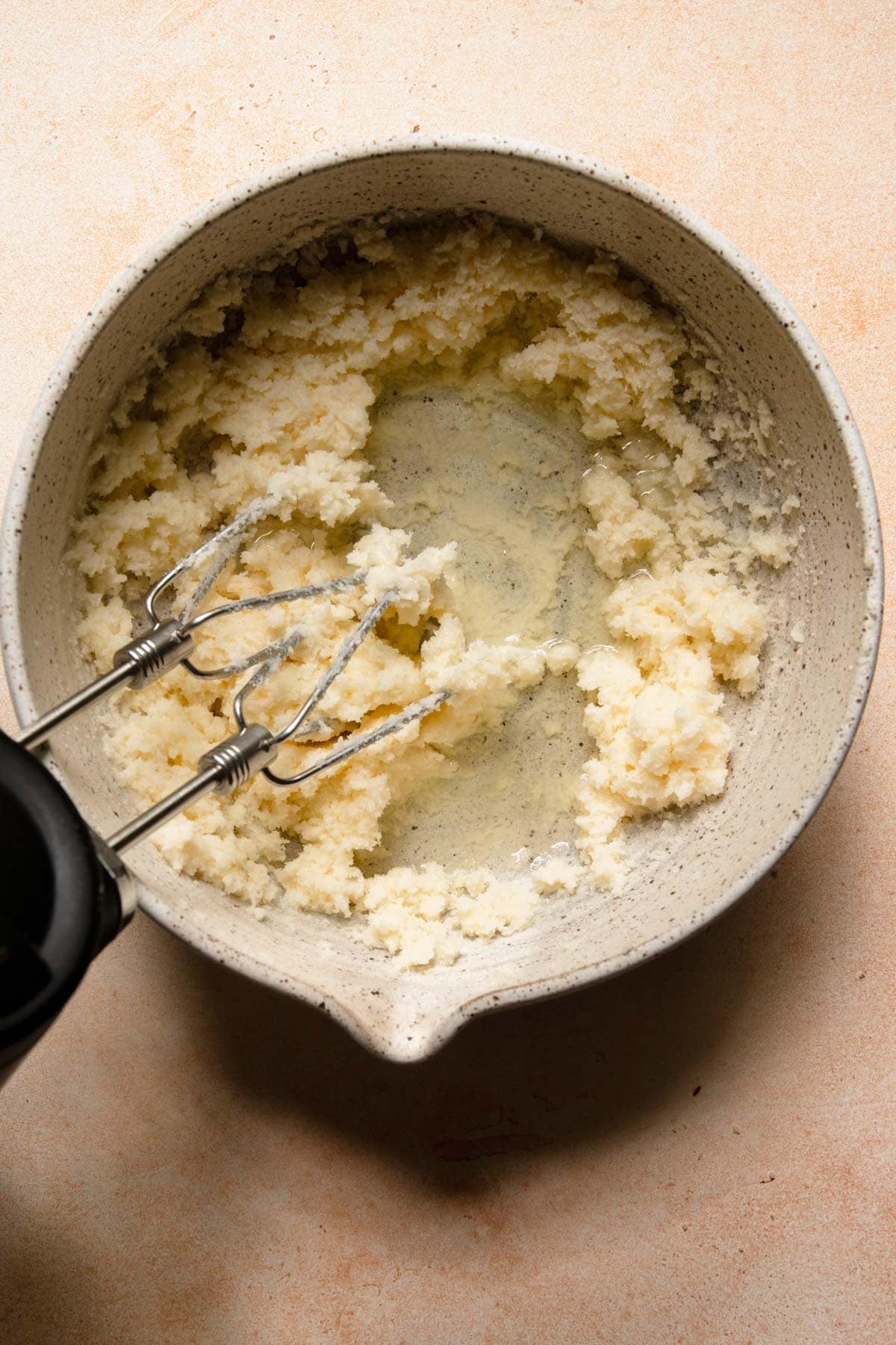A bowl with creamed butter and sugar, oil and stand mixer.