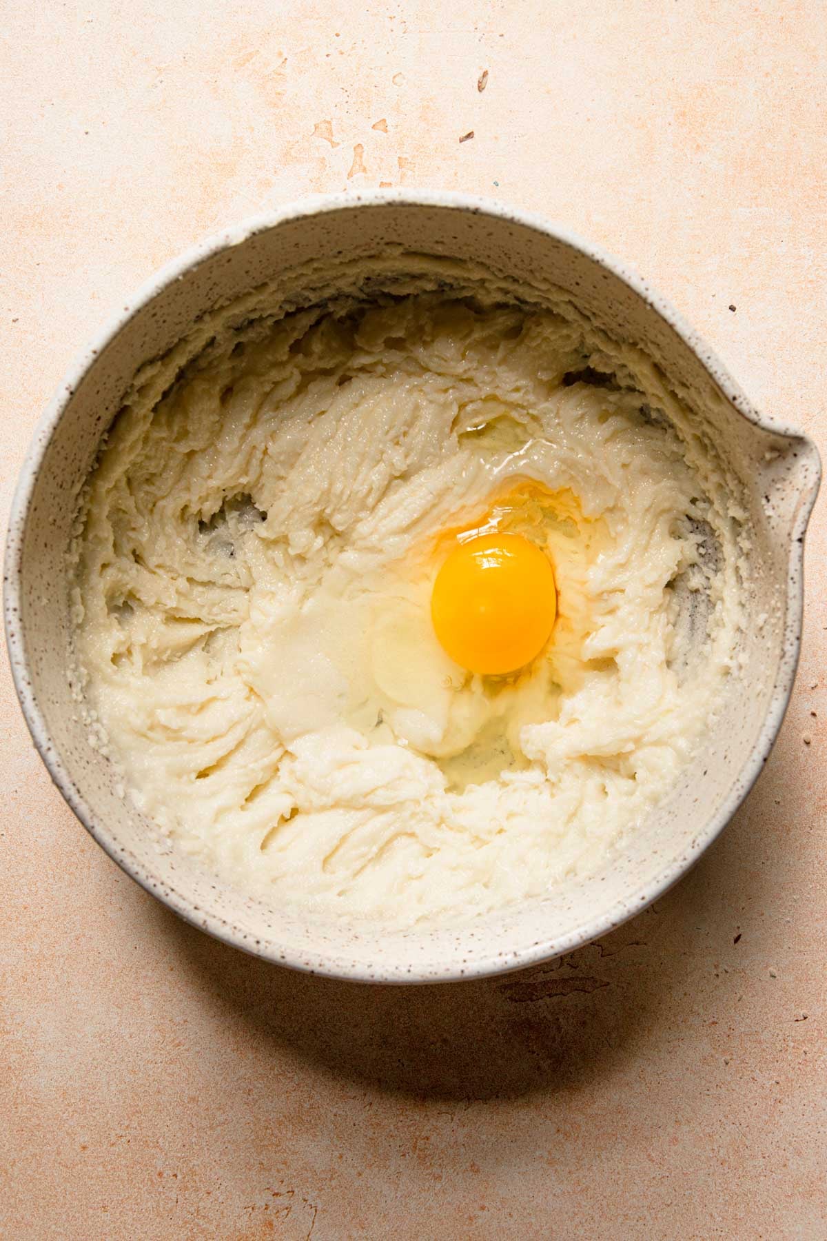 A bowl with creamed butter and sugar and an egg.