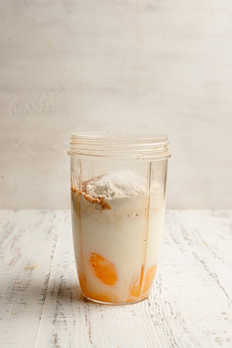 A blender cup with eggs, milk, and flour.