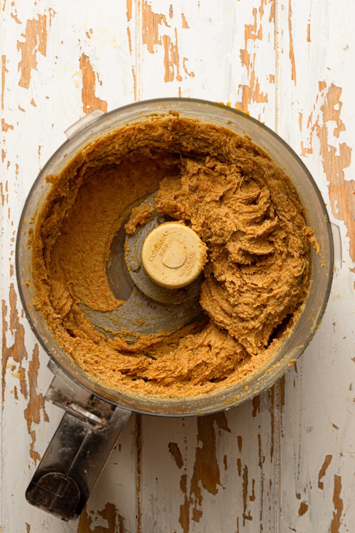 A food processor bowl with orange butter.