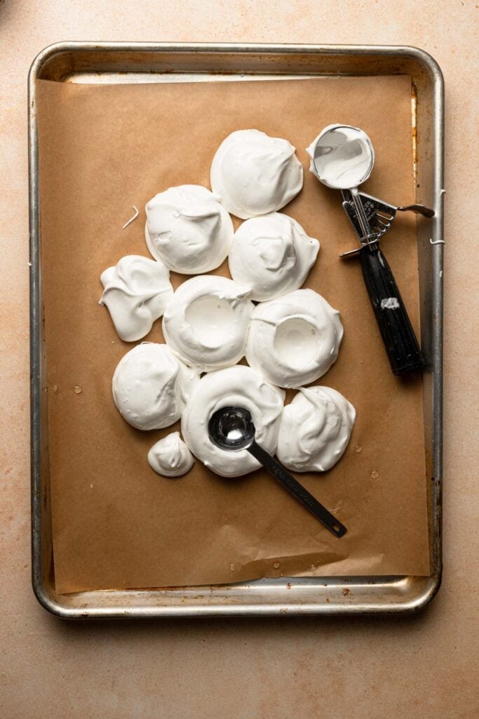 Meringue mounds over a pan lined with parchment paper.