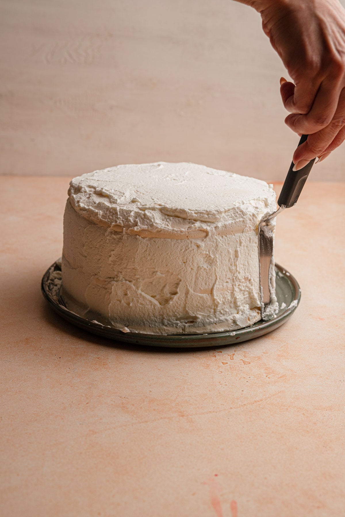 A hand frosting cake with cream.