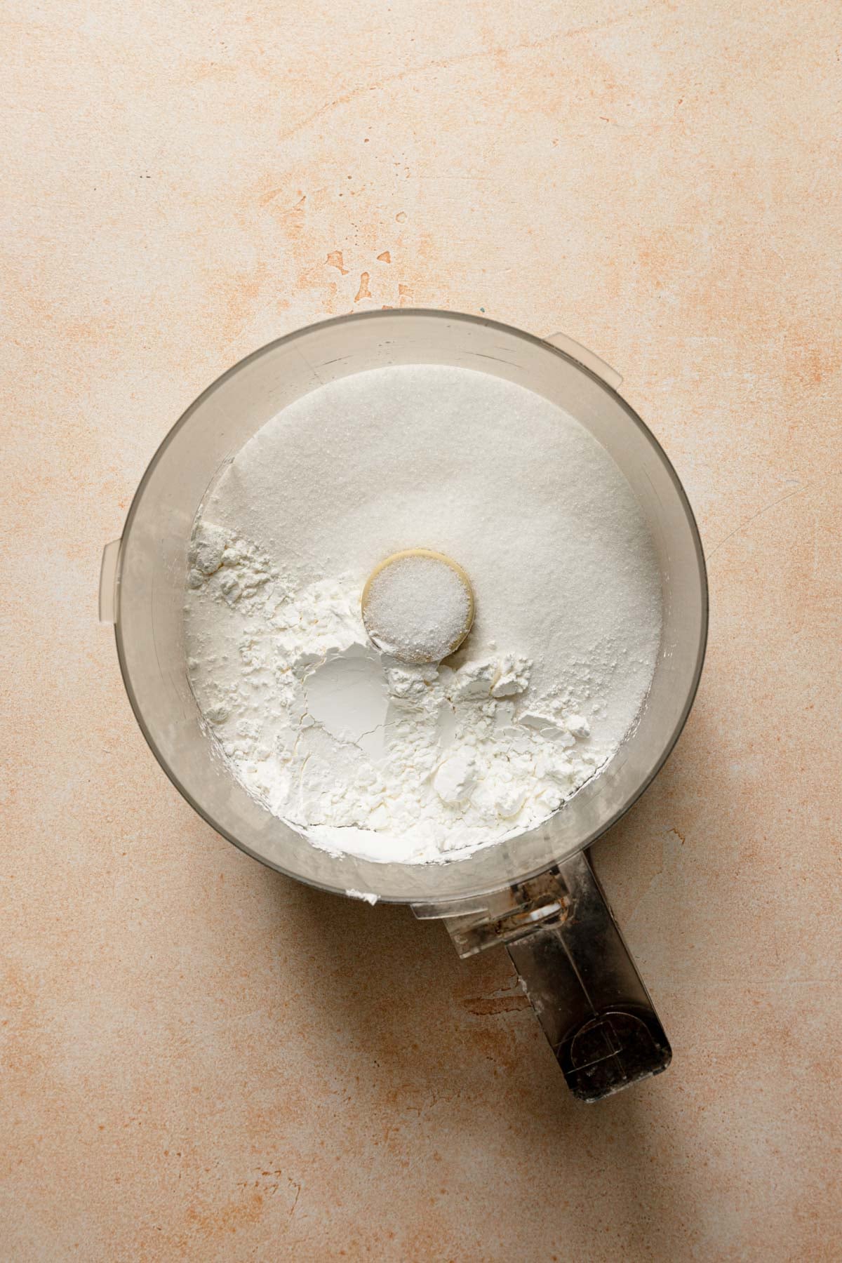 A food processor bowl with sugar and cornstarch.