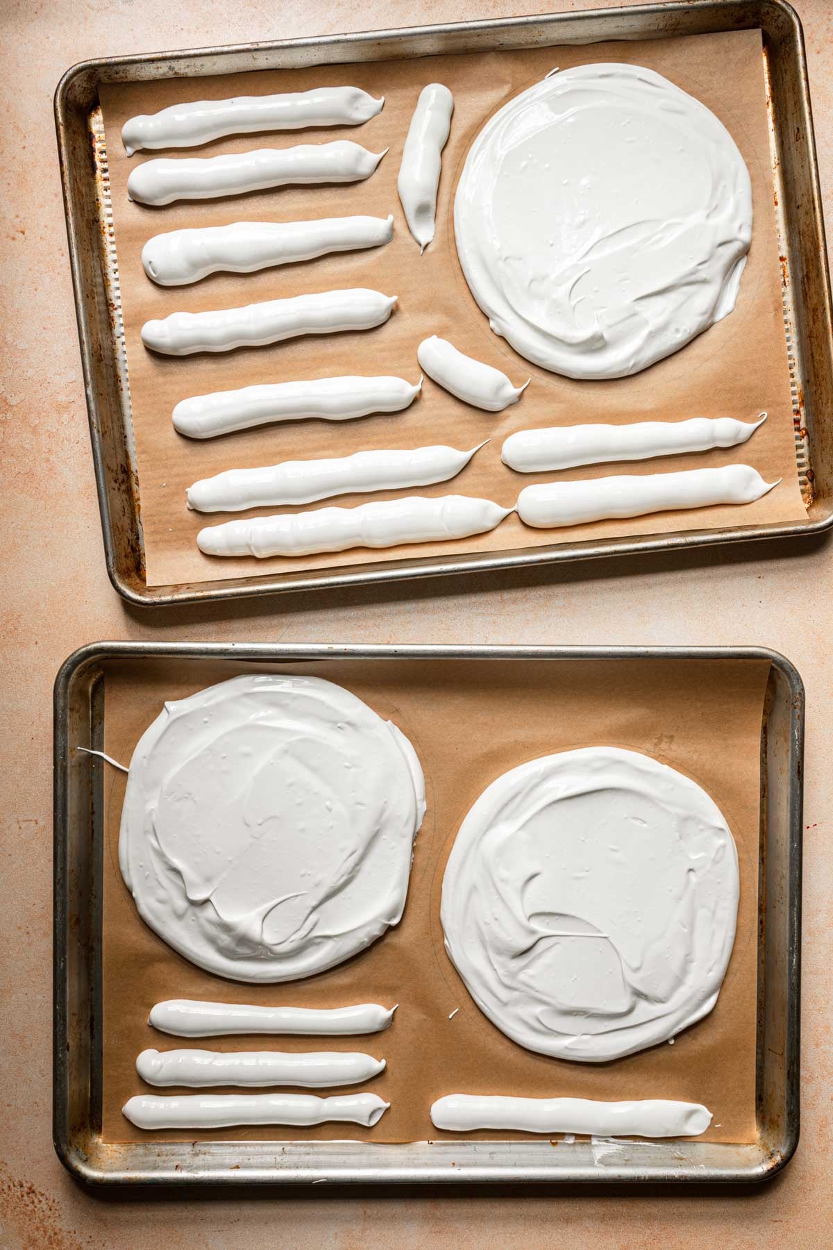 Cookie pans with unbaked meringue disks and logs.