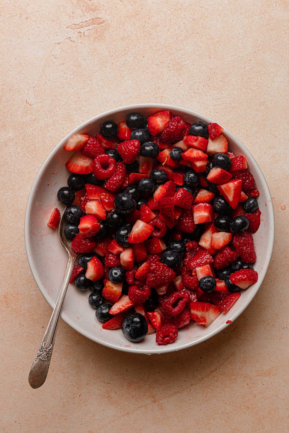 A bowl with mixed berries and a spoon.