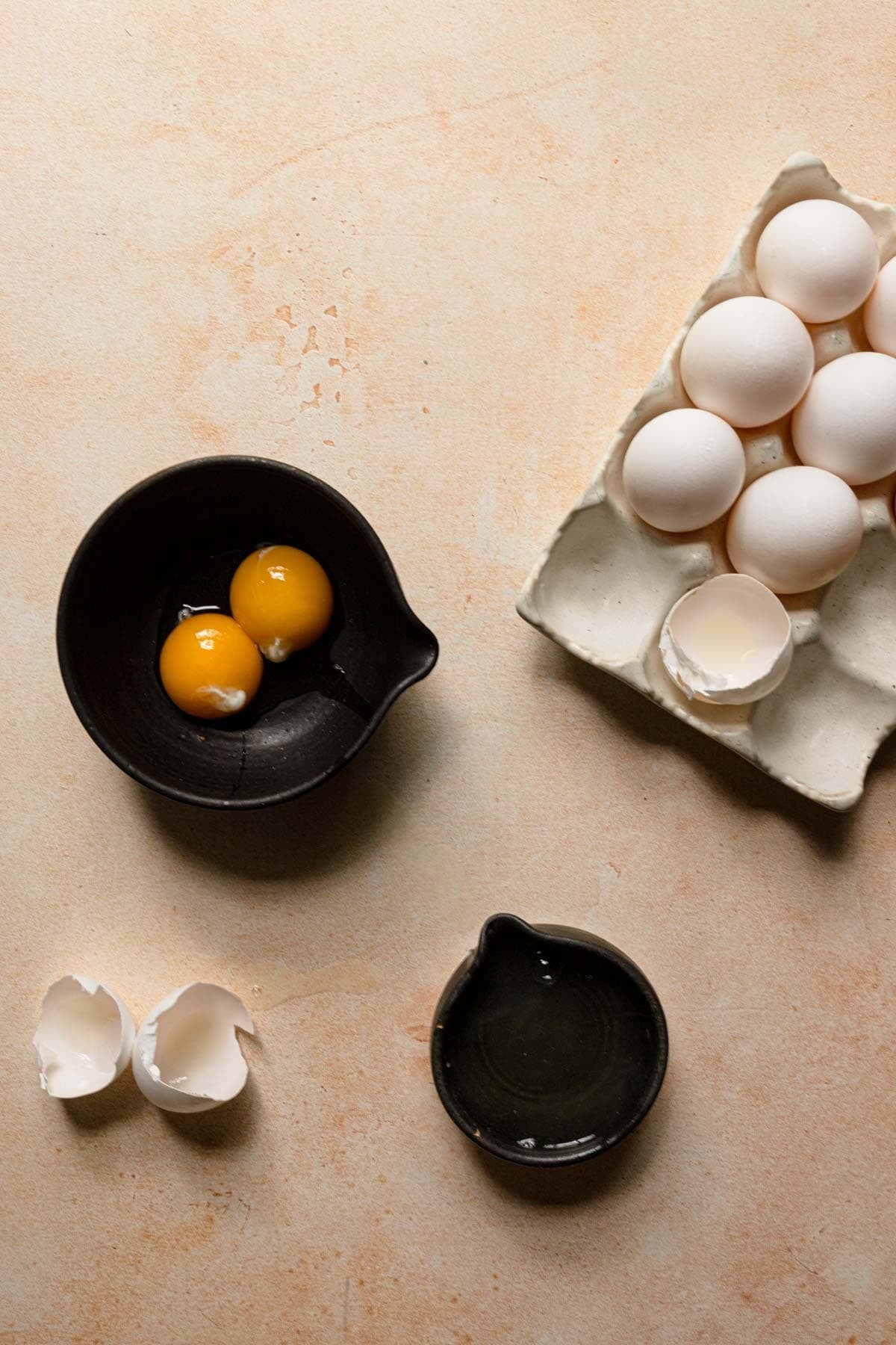 Egg rack next to a bowl with egg yolks, and a bowl with egg whites.