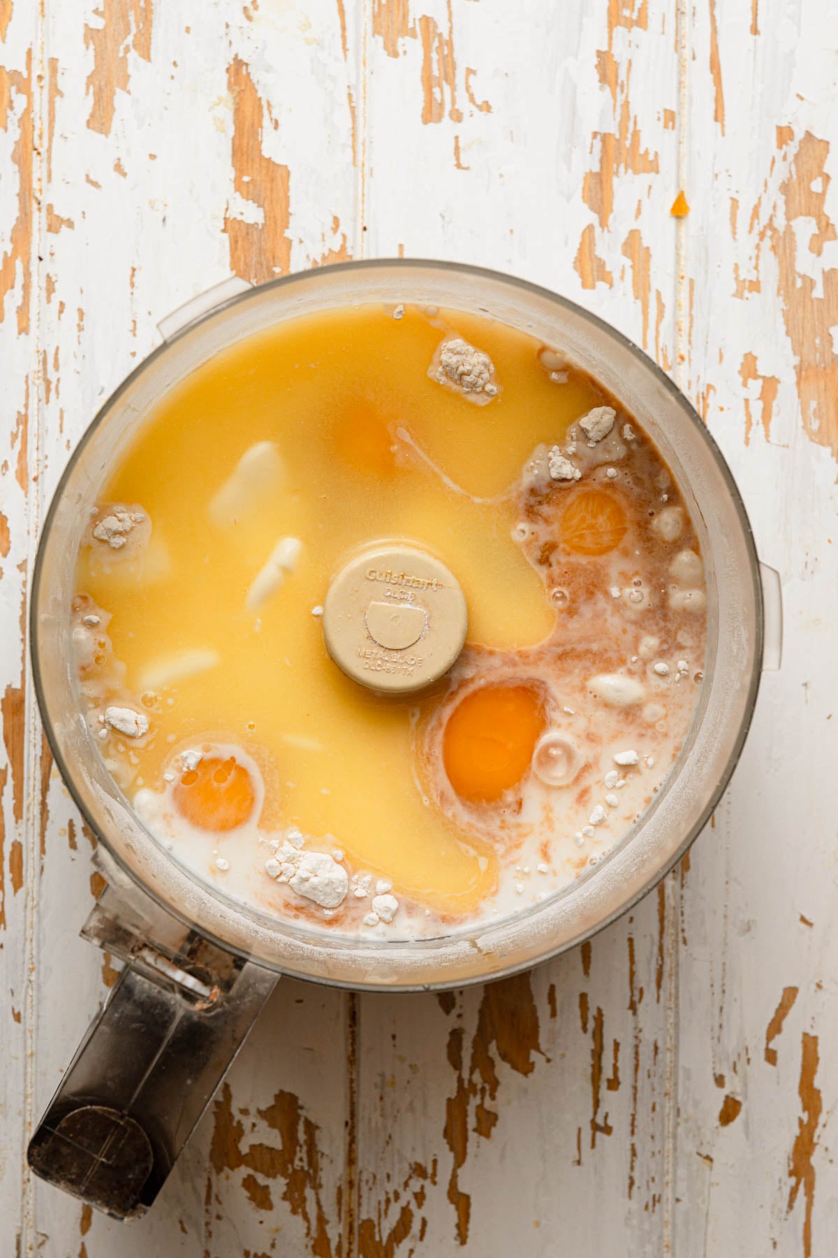A food processor bowl with eggs and milk.