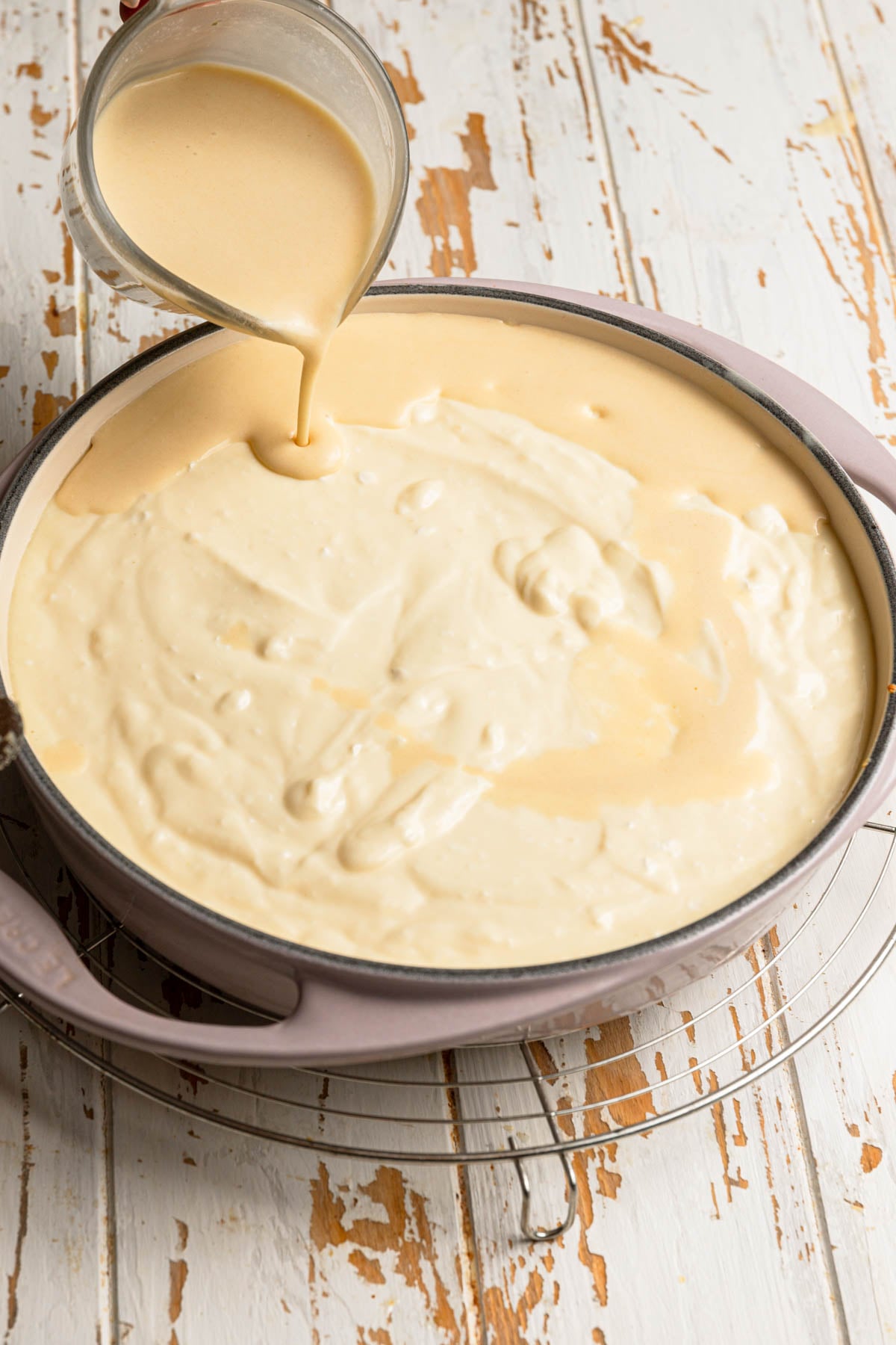 Pouring batter over filling in a dish.