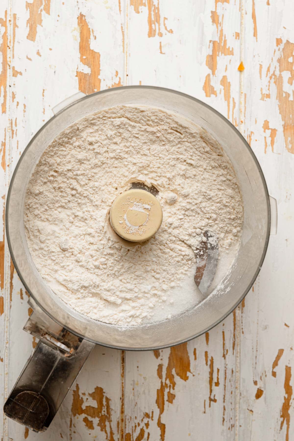 A food processor bowl with flour mixture.