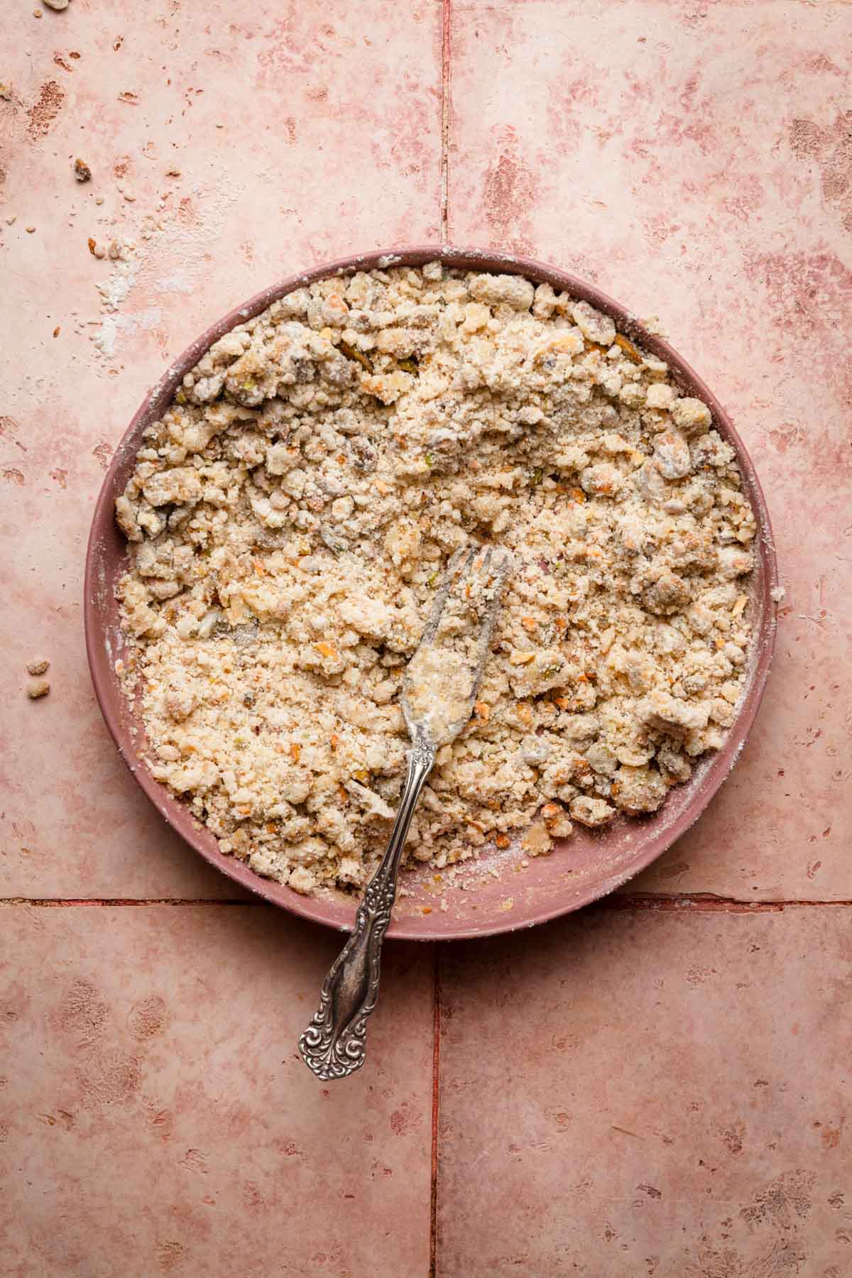 A bowl with pistachio streusel and a fork.