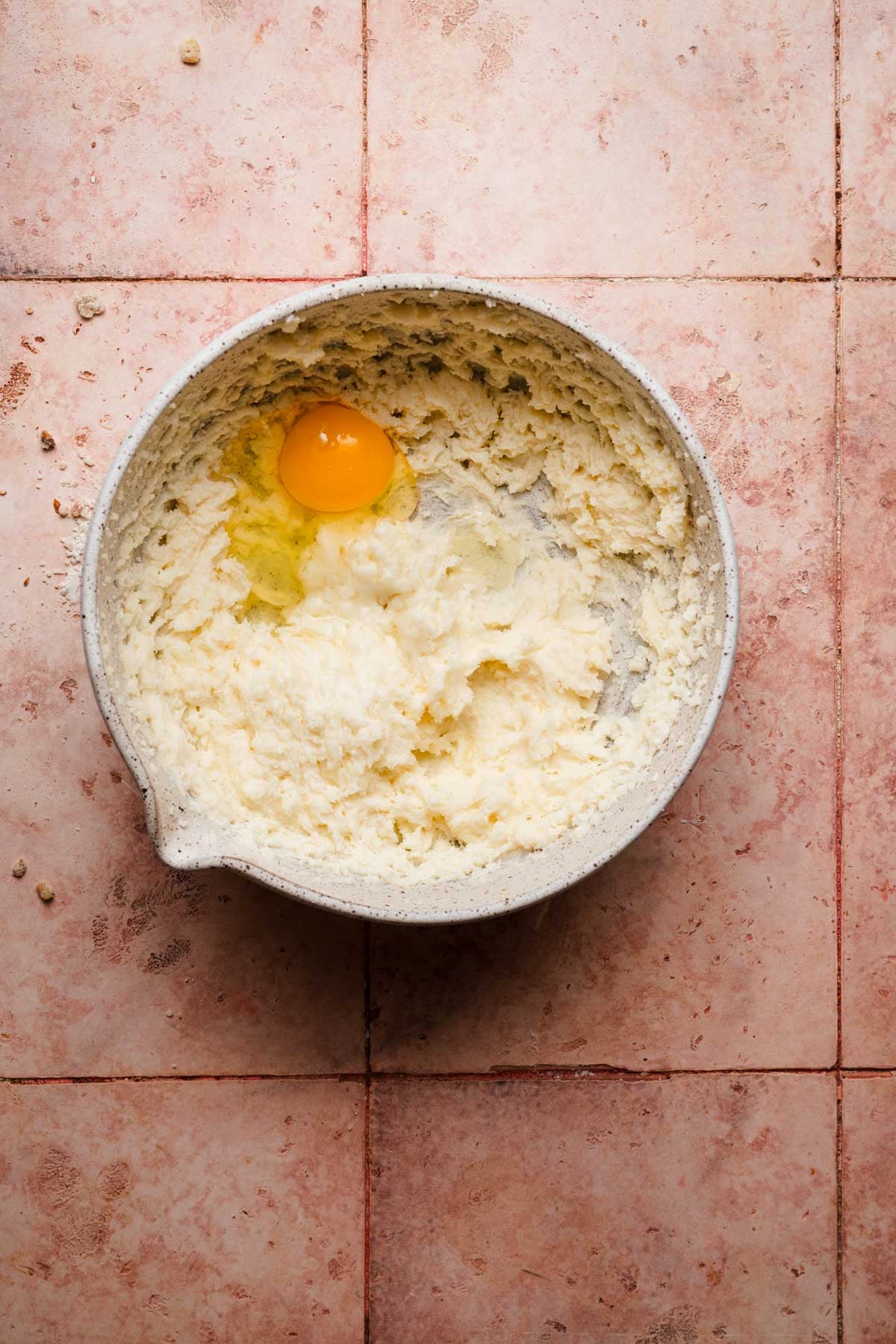 A large bowl with creamed butter and sugar and an egg.