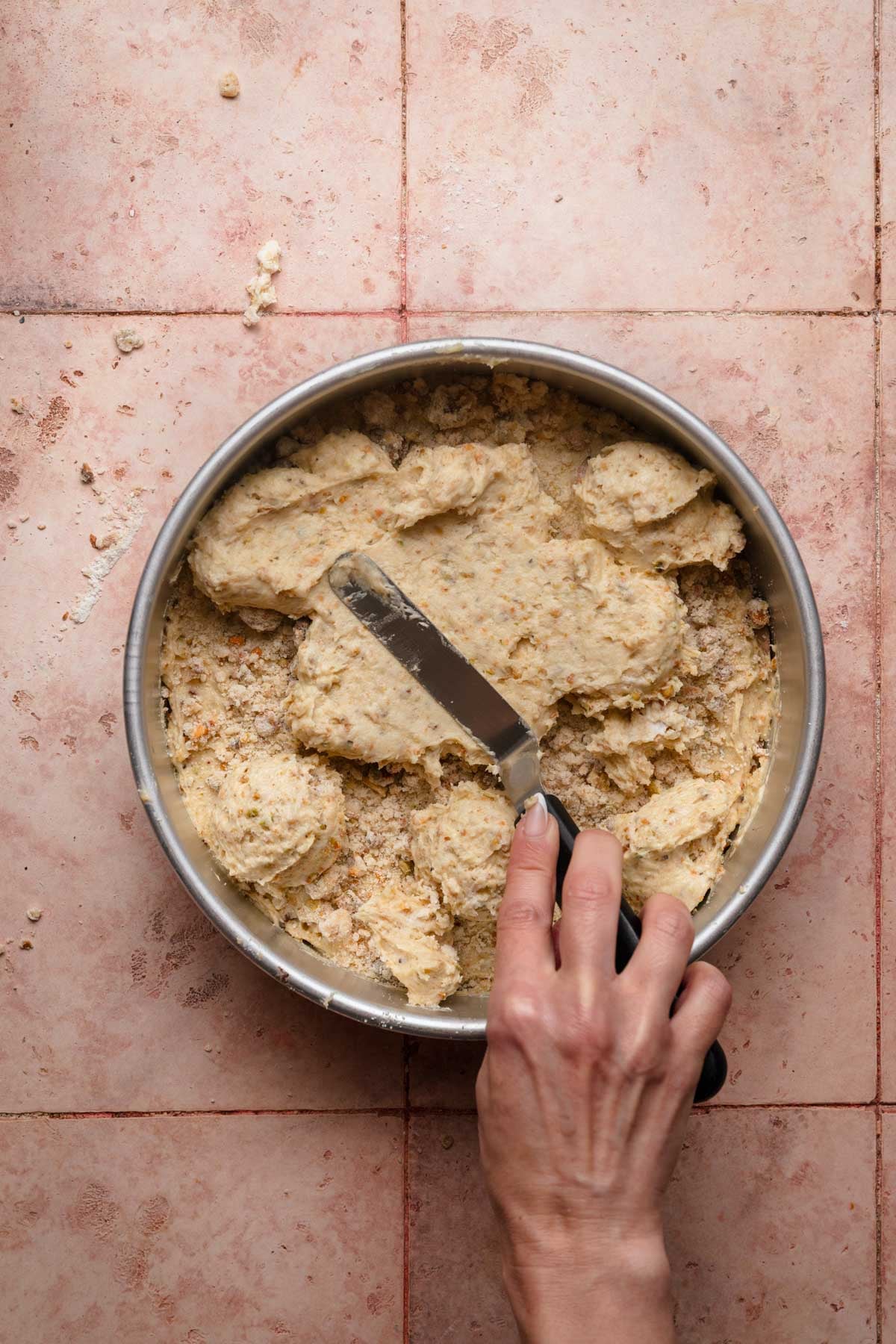 A hand spreading cake batter into a pan.