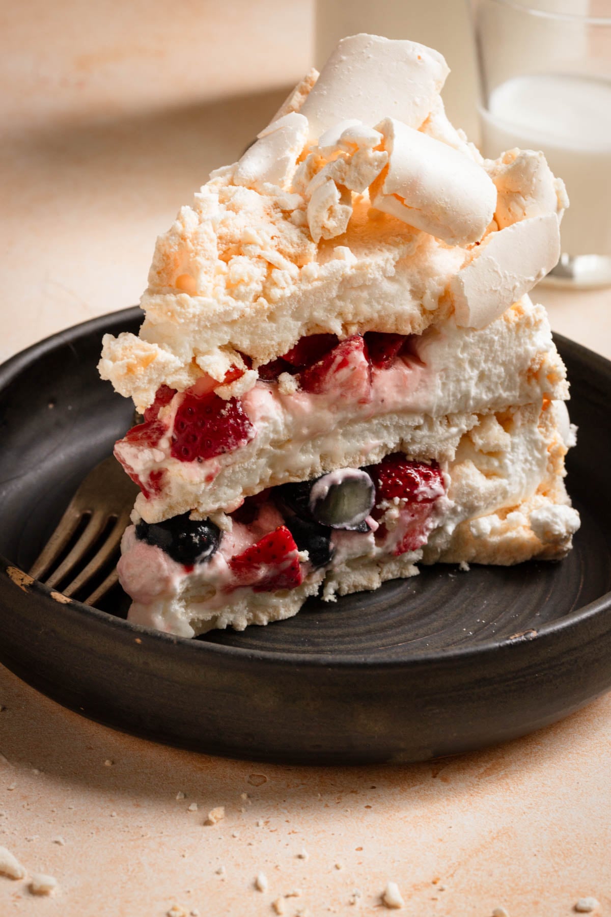 White concorde meringue cake slice filled with mixed berries.